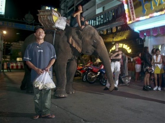 Mahout Supoj Salangam waits for customers in a popular bar area in Bangkok in 1999. Bangkok officials in an attempt to keep elephants off the streets say they will impose a $310 fine on anyone caught handing out bunches of bananas or greenery to the animals.